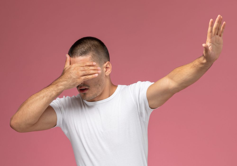 front-view-young-male-white-t-shirt-posing-with-covered-face-pink-background